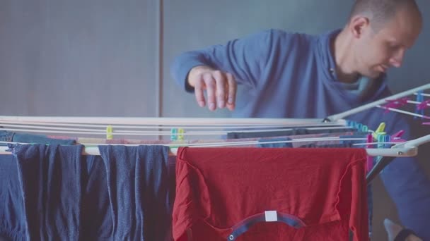 Adam çamaşırları kurutucuya asıyor. Çocuk kıyafetleri. Yalnız baba — Stok video