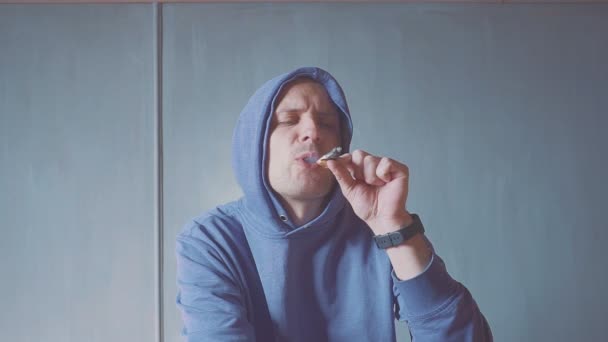 Портрет молодого чоловіка, який палить цигарку в приміщенні крупним планом. дим вогонь світло . — стокове відео