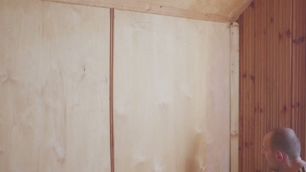 De arbeider schildert een houten zolder. Oppervlaktebehandeling van hout. — Stockvideo
