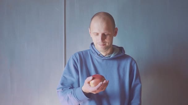 Joven comiendo manzana roja en casa. Retrato de un chico comiendo una manzana fresca y mirando a la cámara . — Vídeos de Stock