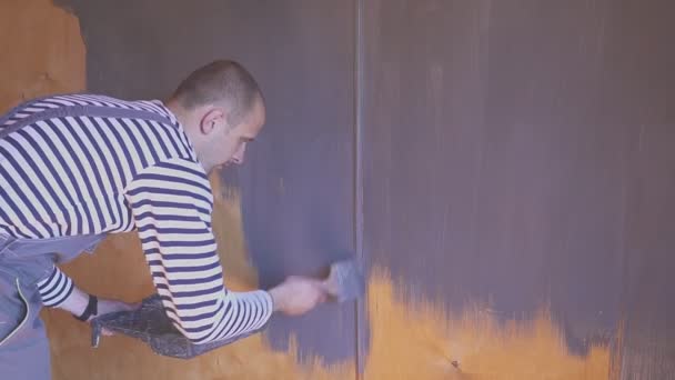 De arbeider schildert een houten zolder. Oppervlaktebehandeling van hout. — Stockvideo