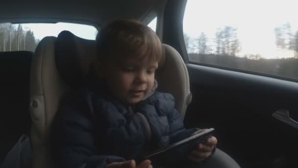 2 år Baby Boy använder telefonen i bilen. mjukt fokus — Stockvideo