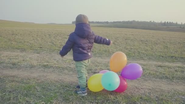 Mutlu bebek çocuk, eğlenceli balonlar ile etrafında çalışan. Açık hava eğlencesi. Akşam gün batımında. — Stok video