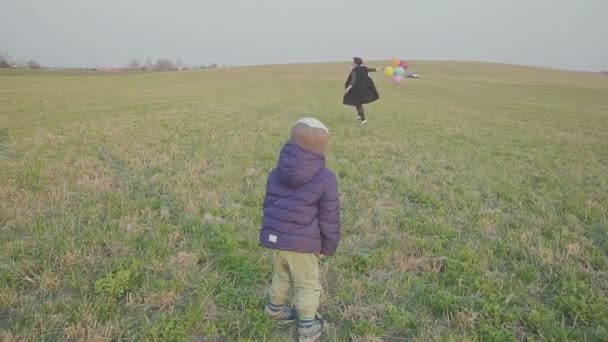 Szczęśliwa młoda matka z małym synem jest chodzenie i radość, syn trzyma balony w ręku. — Wideo stockowe