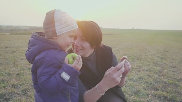 Madre de familia con su hijo pequeño tomando selfies en la noche al aire libre. Posando y sonriendo, disfrutando de la naturaleza . — Vídeos de Stock