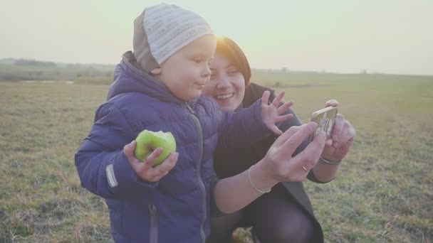 Madre di famiglia con il suo piccolo figlio che si fa selfie la sera all'aperto. Posare e sorridere, godersi la natura . — Video Stock