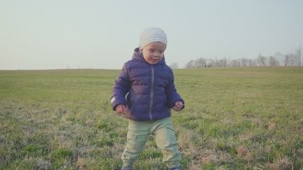 Gün batımında tarlada çimenlerin üzerinde koşan küçük çocuk. — Stok video