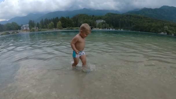 Маленький хлопчик 2 роки у воді лісового гірського озера. Вид ззаду . — стокове відео