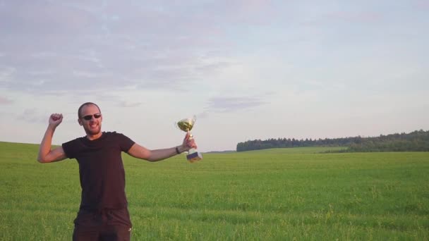 Vítěz s odměnou v jeho rukou zvedá ruce, má úspěch. On skočí a tance — Stock video