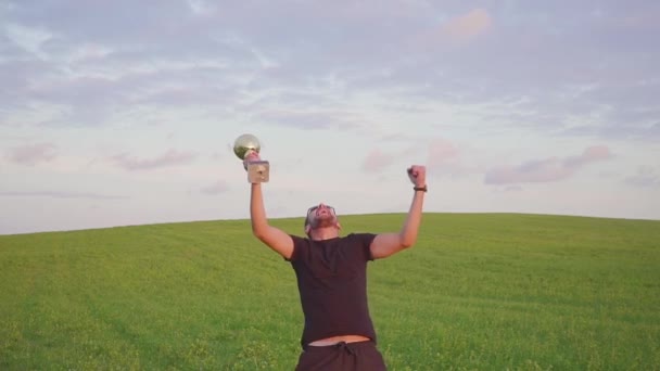 De winnaar met een beloning in zijn handen zijn handen verhoogt, geniet van succes. Hij springt en danst — Stockvideo