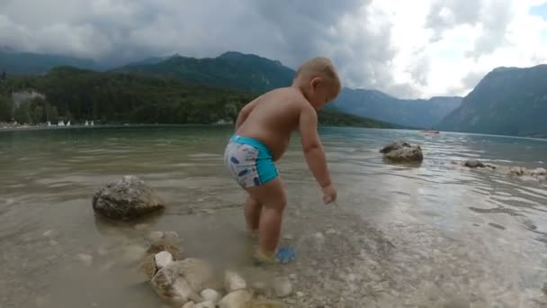 Kleine jongen 2 jaar in het water van bos bergmeer. Uitzicht vanaf de achterkant. — Stockvideo