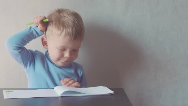 Двухлетний мальчик рисует маркером на альбоме — стоковое видео