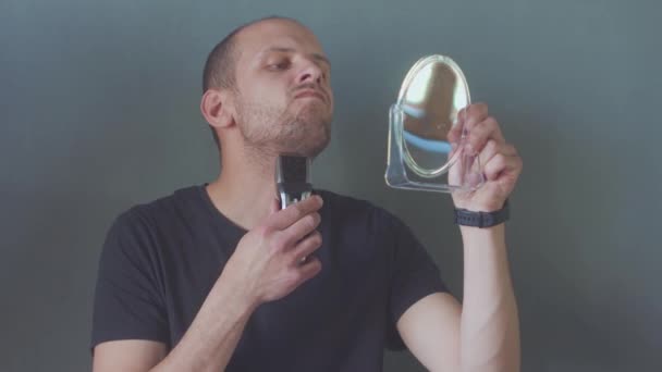 Jonge knappe man in zwart shirt trimmen zijn baard met een trimmer — Stockvideo