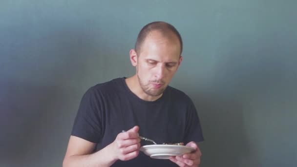 Joven barbudo comiendo y usando teléfono móvil aislado — Vídeos de Stock