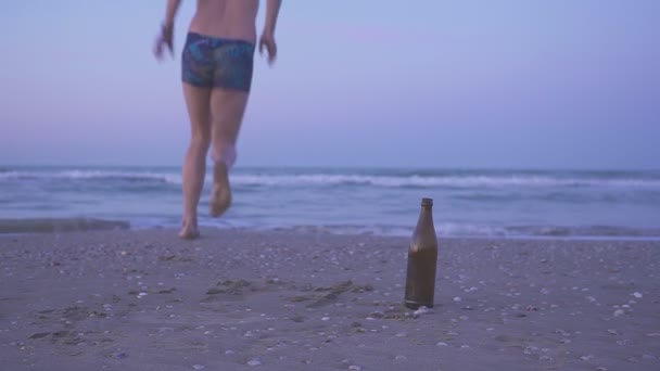 Ein Mann, der sein Bier beendet und ans Meer geht. gesellschaftliches Konzept. Betrunken schwimmen ist gefährlich. — Stockvideo