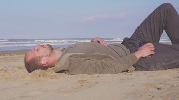 Νεαρός επιχειρηματίας κοιμάται στην άμμο κοντά στη θάλασσα — Αρχείο Βίντεο