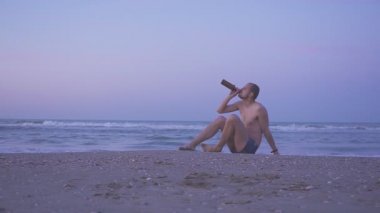 Birasını bitirip denize yüzmeye giden bir adam. Sosyal tema kavramı. Sarhoş yüzmek tehlikelidir..