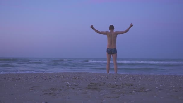 Hombre feliz bailando en la playa al atardecer — Vídeo de stock