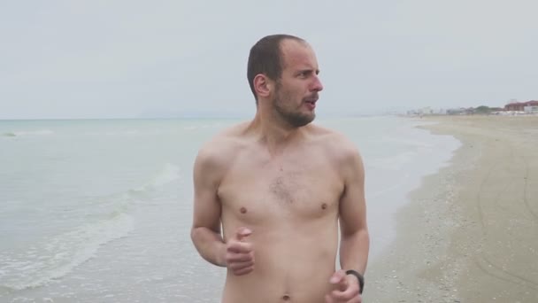 Als sich das Wetter am Strand verschlechterte, zog sich der Mann schnell an. einsamer junger Mann, der am Meeresgrund steht. Trübes Wetter — Stockvideo