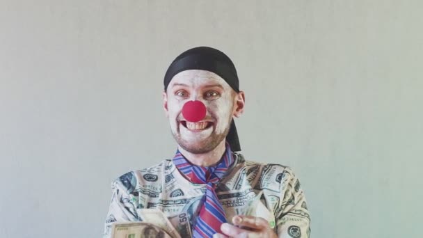 Rolig clown affärsman i en t-shirt gjord av dollar och med dollar i sina händer. Dansar och njuter av sin rikedom. Begreppet stor chef med pengar. — Stockvideo