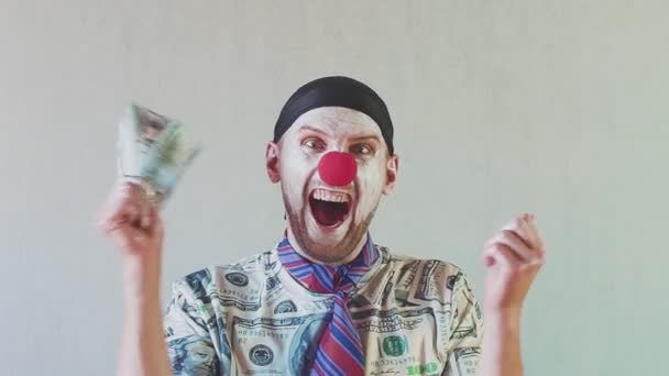 Un buffo uomo d'affari clown con una maglietta fatta di dollari e con i dollari in mano. Ballare e godersi la loro ricchezza. Concetto su capo grande con soldi . — Video Stock