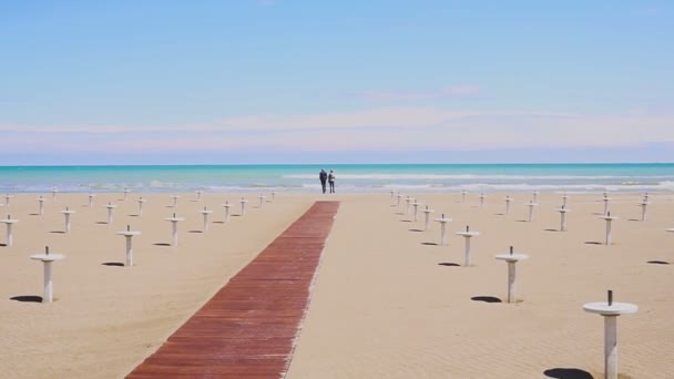 Coppia di ritorno che cammina sulla spiaggia. Un uomo e una donna che vanno al mare — Video Stock