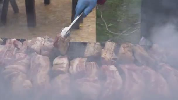 Ocio, comida, gente y concepto de vacaciones. Cocinar patatas fritas carne en un fuego en una fiesta callejera. cocinar carne en la parrilla barbacoa — Vídeos de Stock