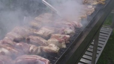 Boş zaman, yemek, insanlar ve tatil konsepti. Bir sokak partisinde ateşte kızarmış et pişirmek. Izgarada et pişirmek