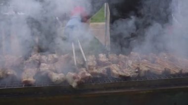 Boş zaman, yemek, insanlar ve tatil konsepti. Bir sokak partisinde ateşte kızarmış et pişirmek. Izgarada et pişirmek