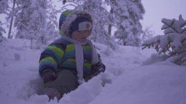Kış orman yaslanarak agaist bir ağaç gövdesi, düşük akşam ışığı, bokeh arka planda bir mutlu bir çocuk çocuk portresi. gece lambası.