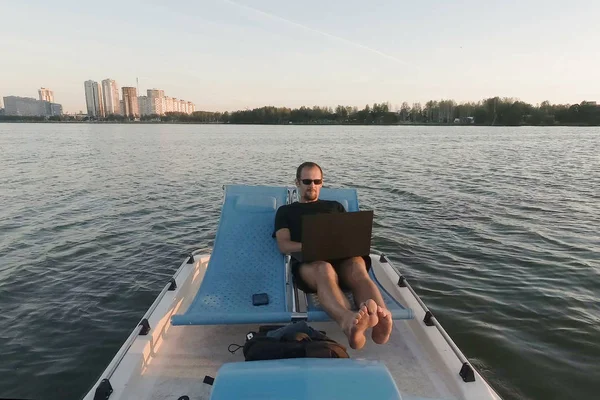 Genç çevirmen bir tekne bilgisayarda çalışır. Uzak iş. Pasif kazanç