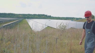 Bir güneş enerjisi istasyonunda çalışan ya da mühendis. Elinde euro banknotları tutuyor, parasını anlatıyor. Gülümseyin ve tamam imzalayın, gibi.
