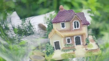 evin para düşüyor. Bozuk para ve ev modeli. Finans ve bankacılık kavramı. Yavaş çekim