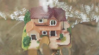 evin para düşüyor. Bozuk para ve ev modeli. Finans ve bankacılık kavramı. Yavaş çekim