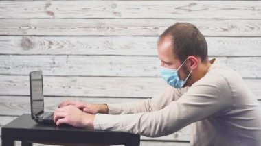 Hasta işadamı sıcaklık ve çalışma office baş ağrısı ile dizüstü bilgisayar kullanın. Öksürük ile yüz maskesi giyen adam.