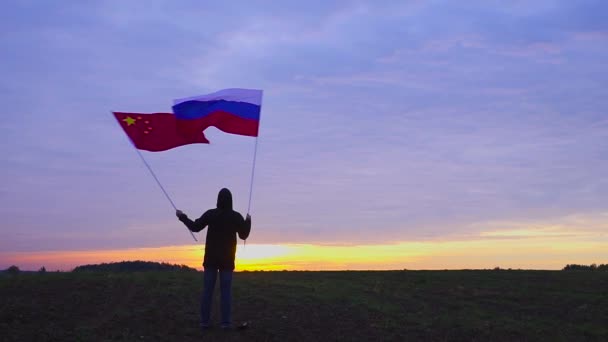 俄罗斯和中国国旗在风中飘扬的画面。在风景中挥舞旗帜。俄罗斯中国国旗. — 图库视频影像