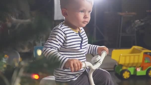 Junge spielt mit gespendetem Fahrrad in der Nähe des Weihnachtsbaums — Stockvideo