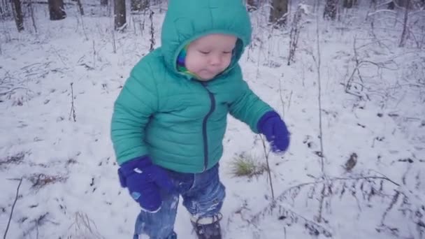 Niño pequeño camina y juega en la madera nevada, niño caminando en el bosque de invierno cámara lenta — Vídeos de Stock