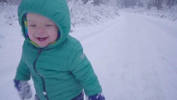 Menino caminha e brincando em madeira nevada, criança andando na floresta de inverno câmera lenta — Vídeo de Stock