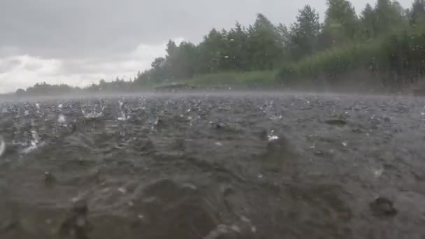 Starke Regentropfen fallen auf die Wasseroberfläche des Sees. Zeitlupe — Stockvideo
