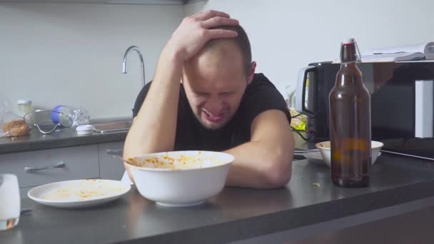 Muž s kocovinou u stolu v kuchyni. po oslavě — Stock video