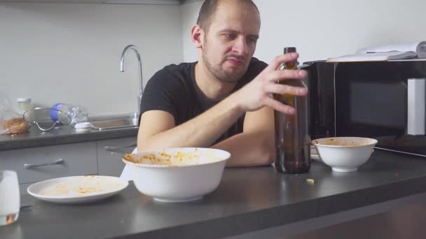 Man med en baksmälla vid bordet i köket. efter fest — Stockvideo