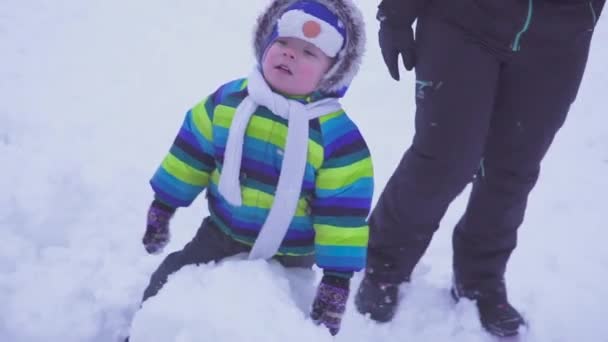 Portrait d'un enfant garçon heureux dans la forêt d'hiver penché contre un tronc d'arbre, faible lumière du soir, bokeh en arrière-plan. lumière de nuit . — Video