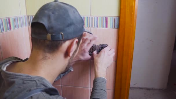 Close-up of an electrician with a screwdriver seting up a white outlet. — Stock Video