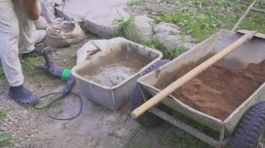 Bir işçi çimento karışımı hazırlar. Bir matkap ile engeller. Close.