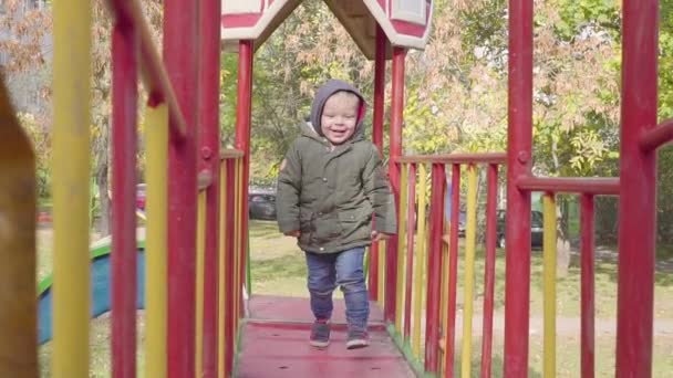 Garçon joyeux courant sur le pont sur l'aire de jeux — Video