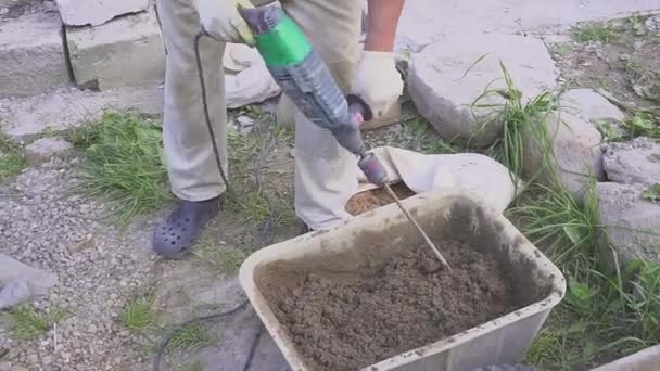 Ein Arbeiter bereitet eine Zementmischung vor. behindert mit einem Bohrer. Nahaufnahme. — Stockvideo