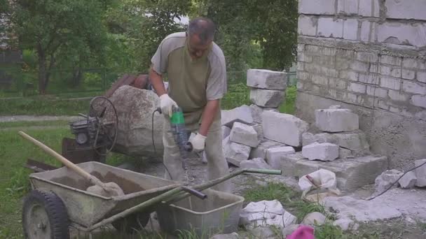 Pracownik przygotowuje mieszaninę cementu. Utrudnia wiertarki. Zbliżenie. — Wideo stockowe