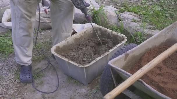 Um trabalhador prepara uma mistura de cimento. Hinders com uma broca. Close-up . — Vídeo de Stock