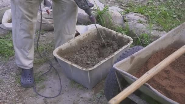 Ein Arbeiter bereitet eine Zementmischung vor. behindert mit einem Bohrer. Nahaufnahme. — Stockvideo